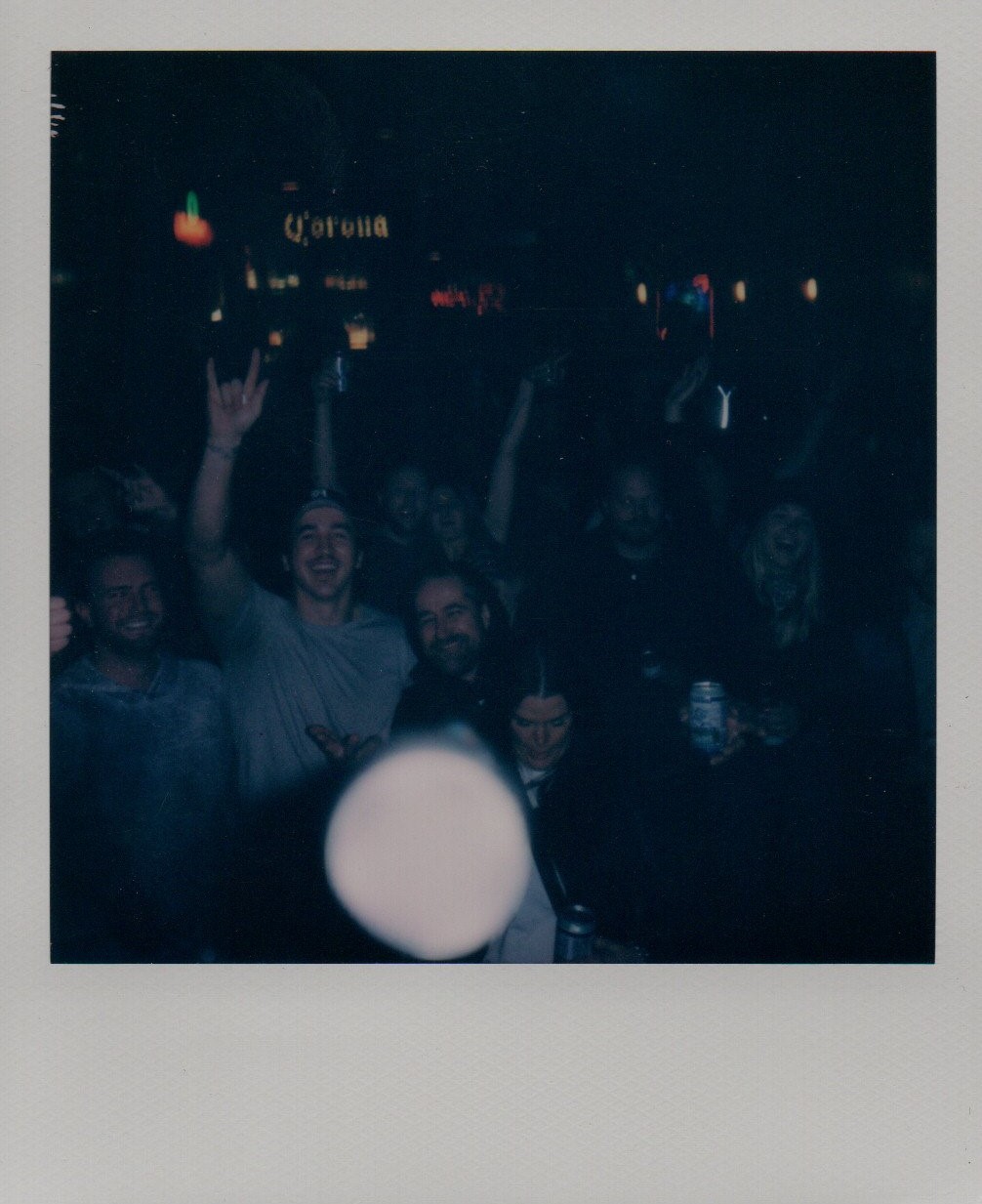 A crowd of people enjoying the music and raising their arms in the air.