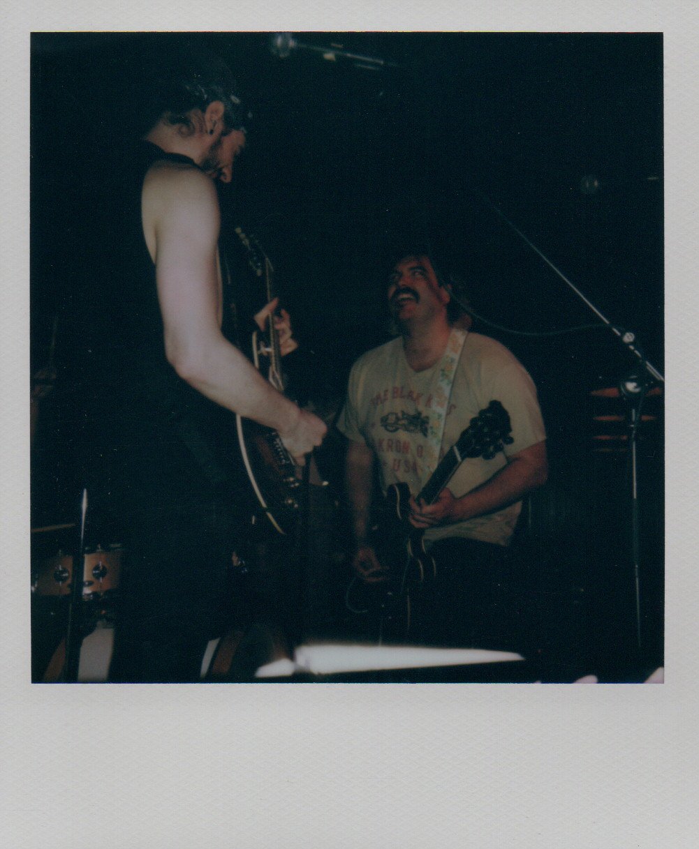 Nevil and Quinn playing guitar and singing on stage.